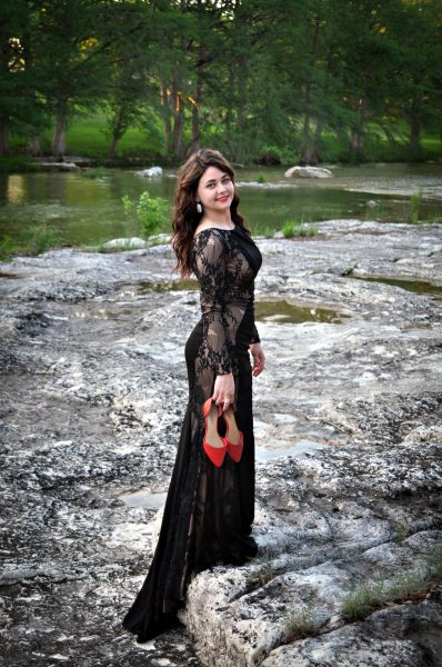 outdoor portrait of young woman in black with red shoes
