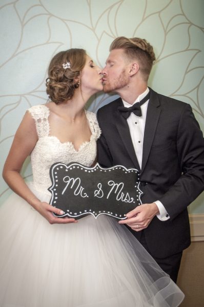Bride & Groom kissing with sign